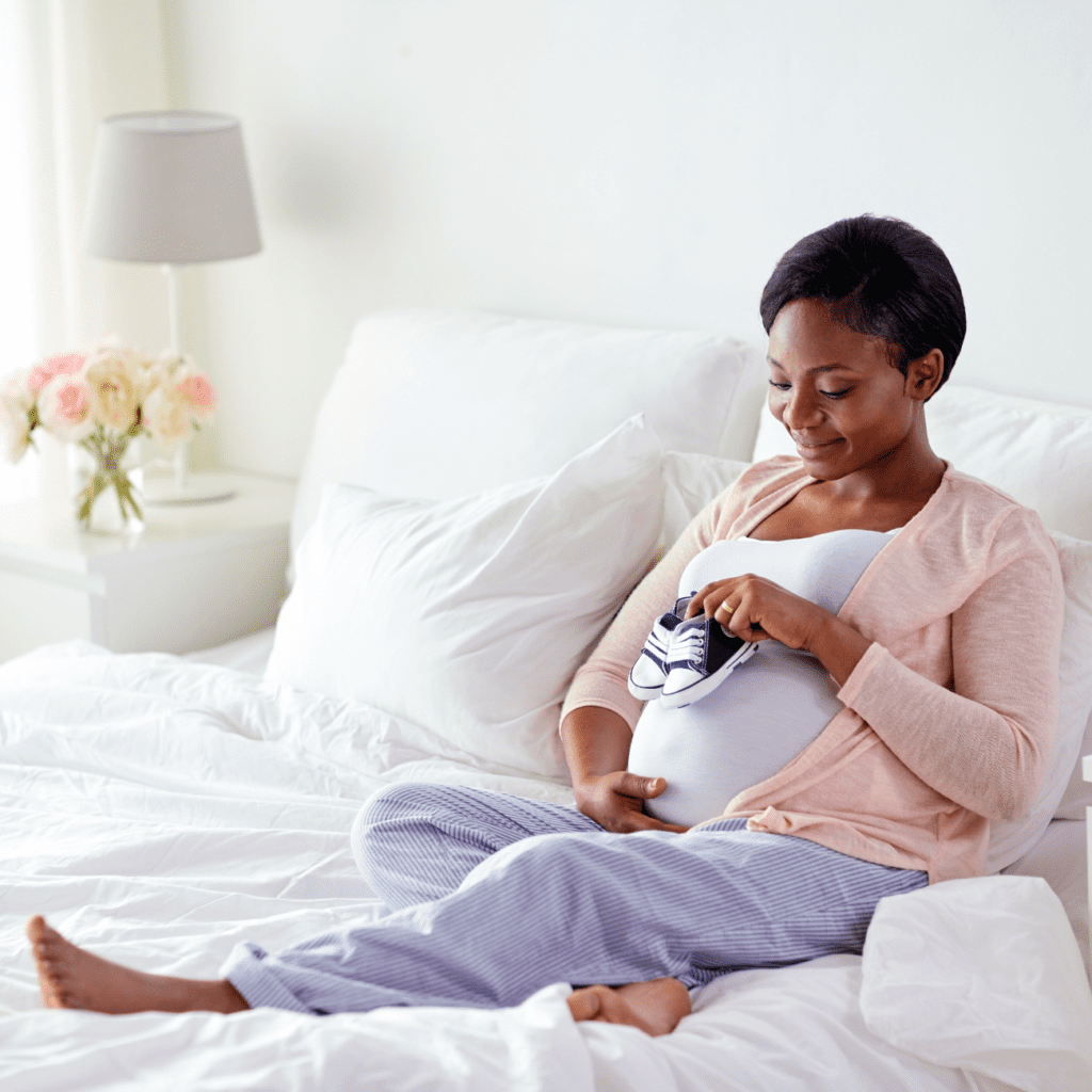 A woman sitting on the bed holding her baby