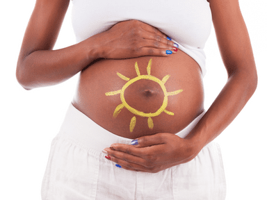 A pregnant woman with a sun drawn on her belly.
