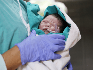 A person holding an infant in a hospital.