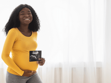 A woman holding up her baby ultrasound picture.