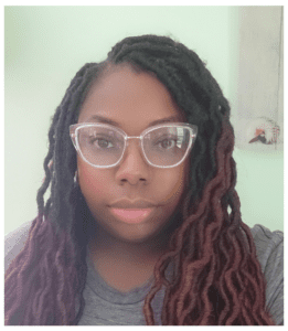 A woman wearing glasses and dreadlocks.