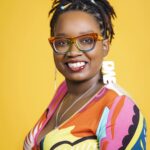 Smiling person with colorful attire, yellow background.
