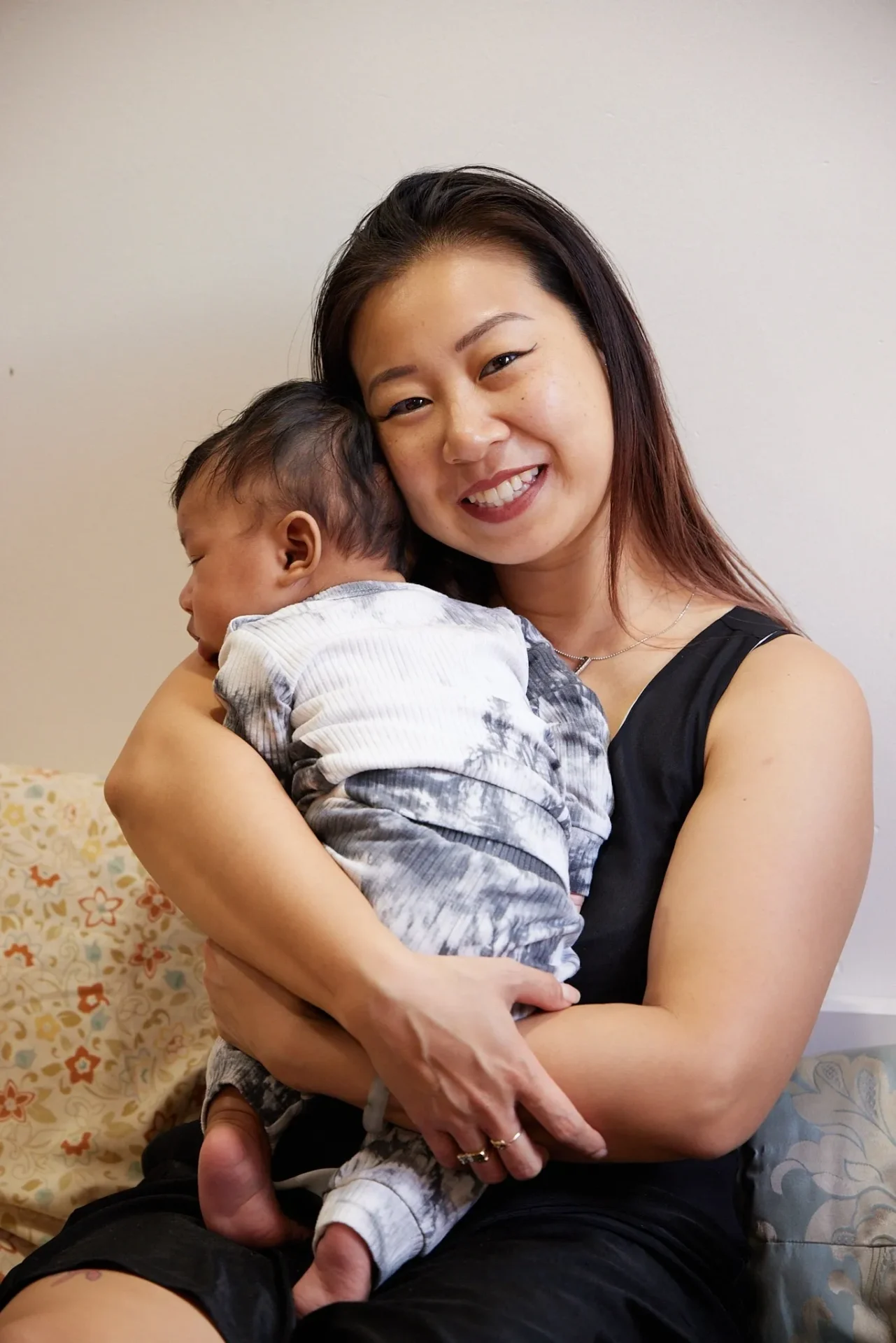 Smiling woman holding a sleeping baby.