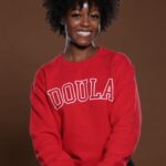 Smiling person in red "Doula" sweatshirt.